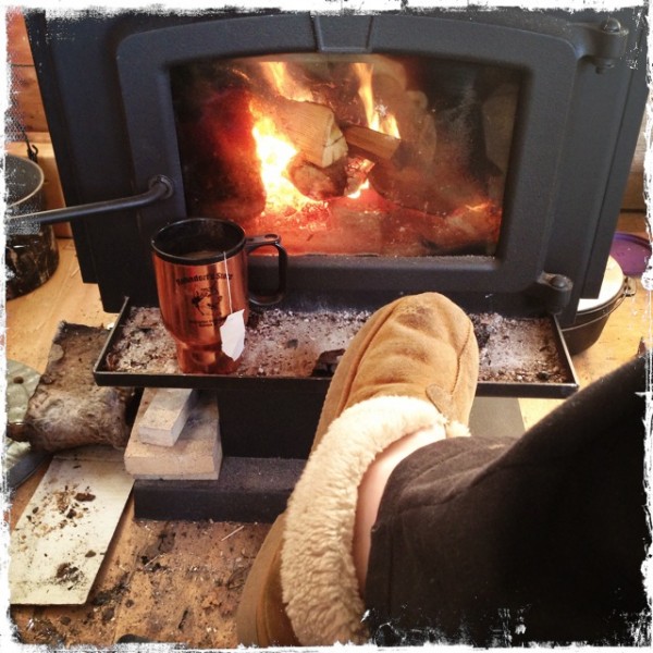 Cozy in front of a wood stove with a cup of tea.